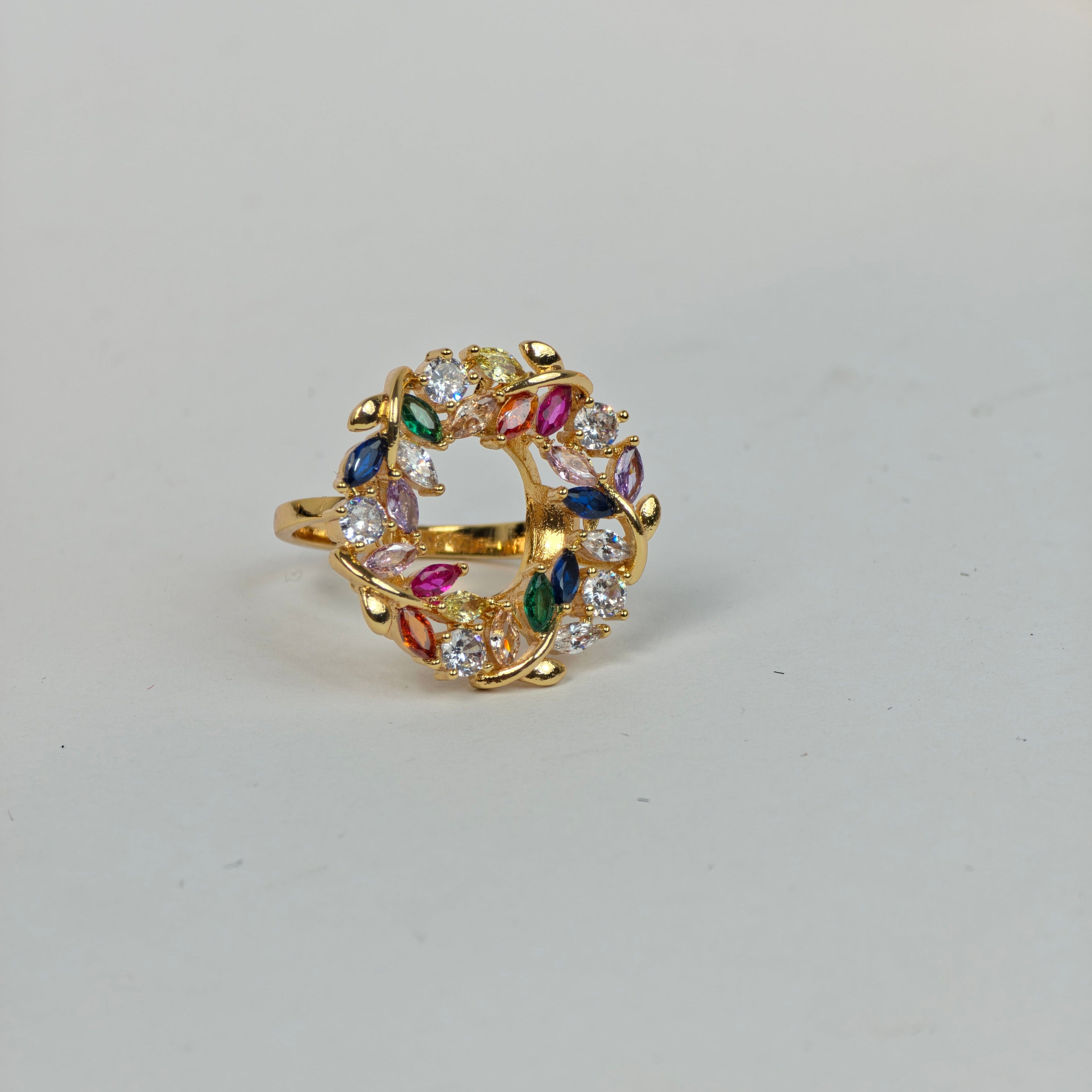 Gold ring with colorful gemstones on a light gray background