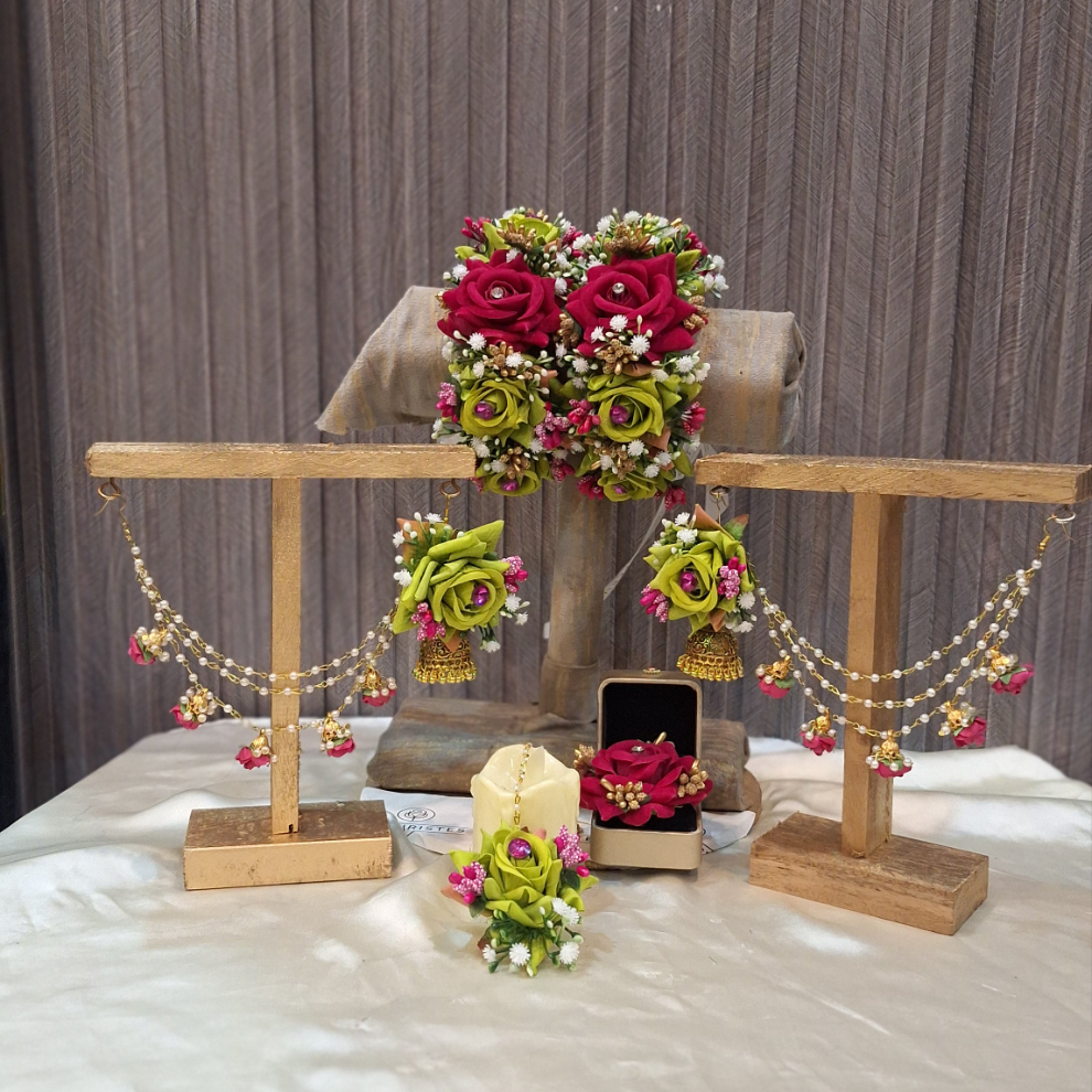 Decorative jewelry set with flowers and necklaces on a wooden stand against a striped wall.