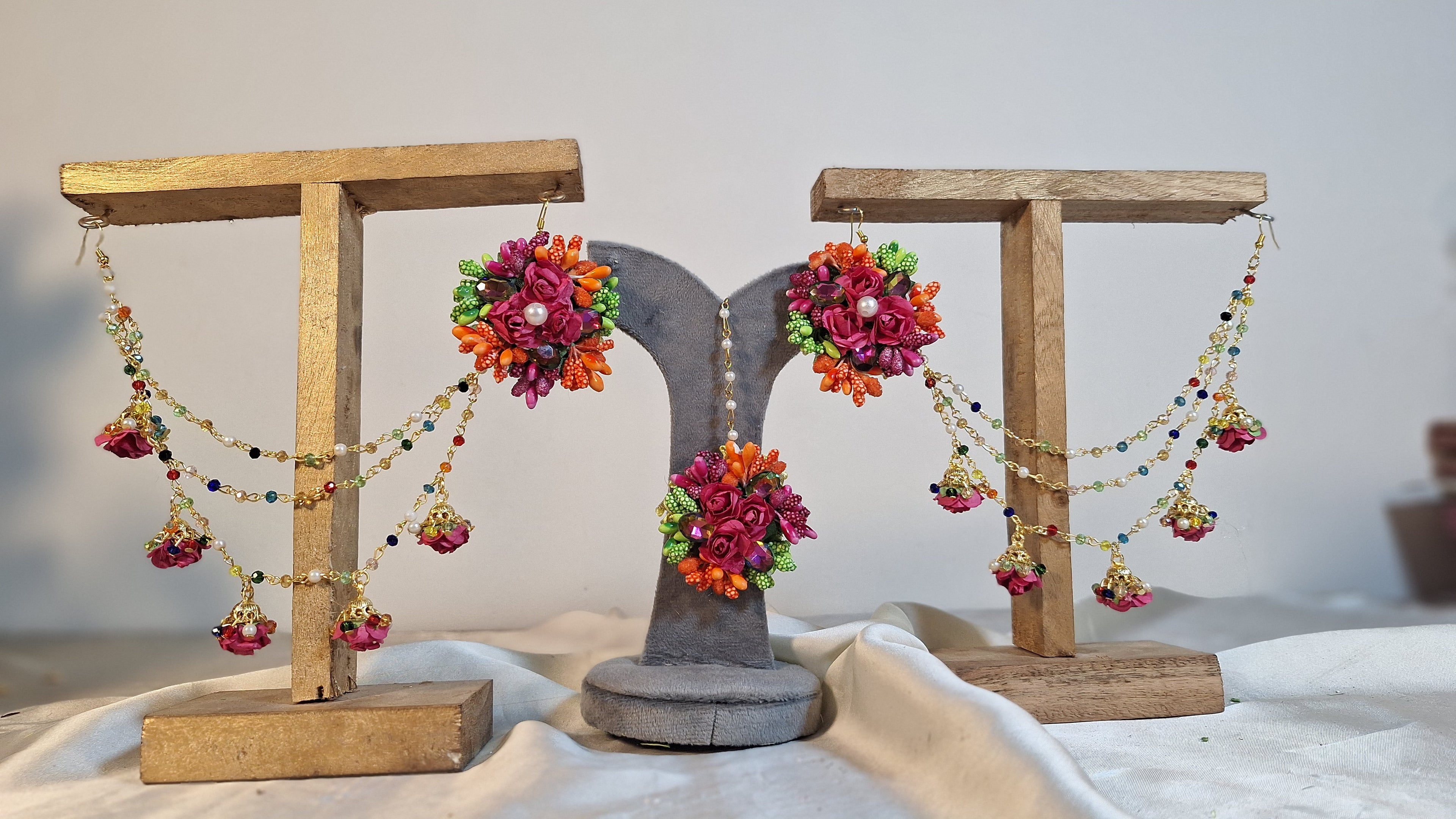 A detailed close-up shot showing the variety of vivid artificial focal flowers, elegant tracking chains, and matching bindiya on the Colour Bloom set.