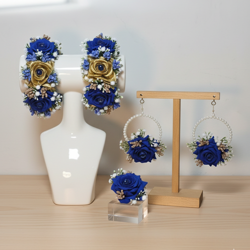 Set of blue and gold floral earrings displayed on a mannequin bust and wooden stand.