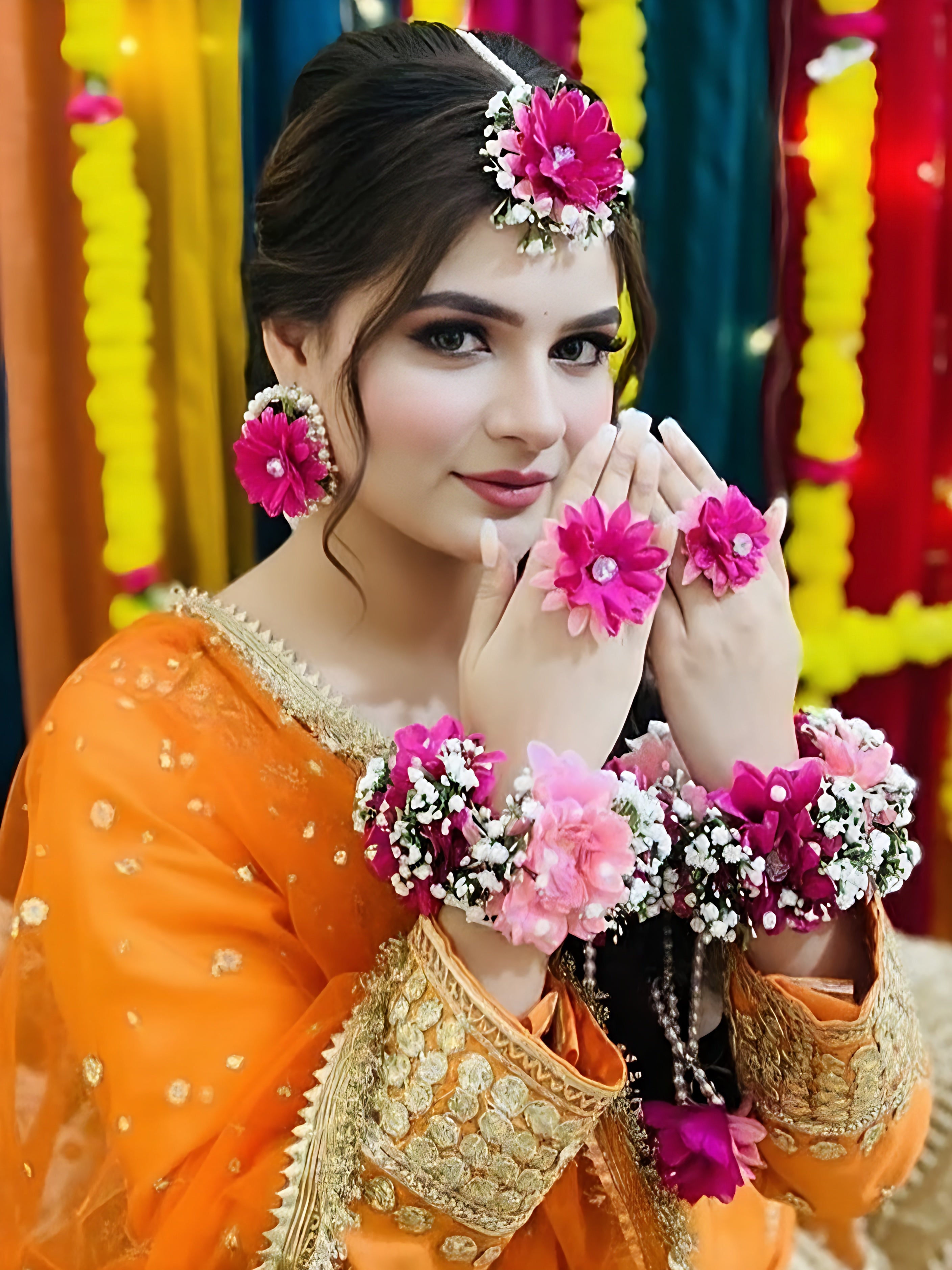 Woman in traditional orange and gold outfit with floral accessories against a colorful background