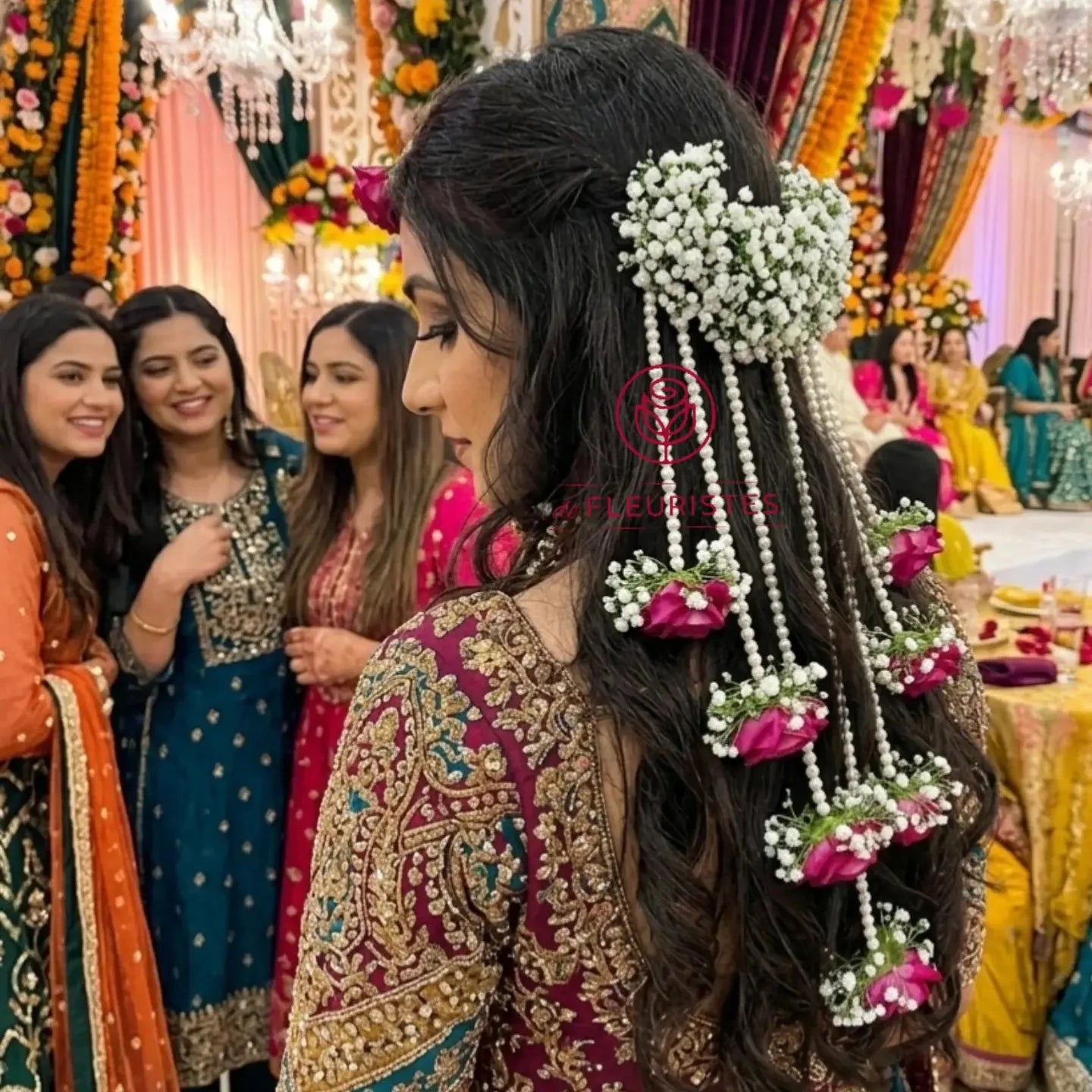Woman with floral hair accessories at a festive event with decorations and people in colorful attire.
